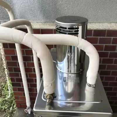 屋外に据え付けた長府製作所の石油給湯器の配管と排気筒